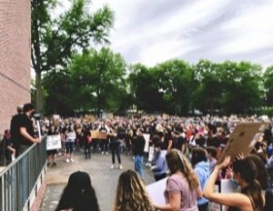 A large crowd is gathered outside to rally, with many people holding signs.